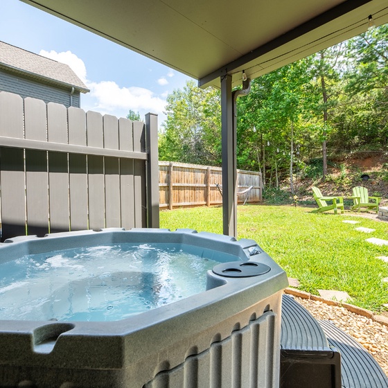 Slip into your private hot tub and let the warm jets melt away the day's stress, framed by lush green trees and a spacious backyard perfect for evening gatherings.