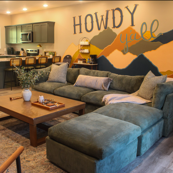 Settle into your open-concept retreat where a plush sectional invites you to unwind beneath playful mountain art. The fully-equipped kitchen and warm, welcoming vibe make this space perfect for gathering.