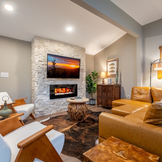 Settle into rich leather seating where your stone fireplace adds warmth and ambiance. Natural light streams through the windows, creating a welcoming retreat perfect for unwinding after your adventures.