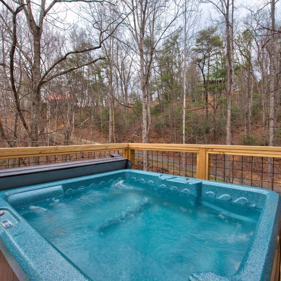 Your private hot tub bubbles away on the deck, surrounded by peaceful woods for ultimate relaxation.