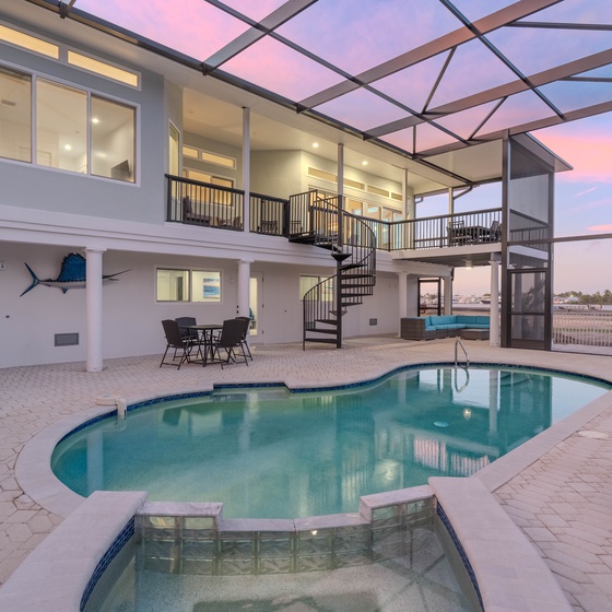 Stunning waterfront villa with screened pool area perfect for sunset swims and outdoor dining under the twilight sky.