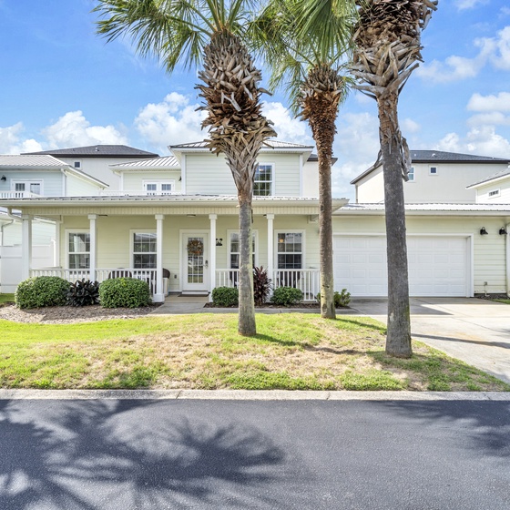 Welcome to Take It Breezy, a charming coastal home featuring tropical landscaping with mature palm trees and a welcoming front porch in a peaceful residential neighborhood.