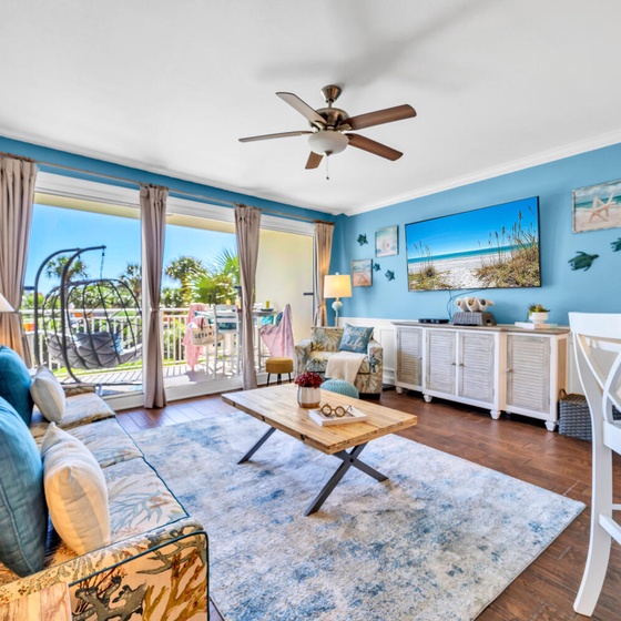Welcome to Sterling Shores 204 - Coastal Calm! Relax in your coastal-themed living room with ocean blues, comfortable seating, and balcony access for the perfect beach getaway.