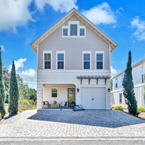 Welcome to Serenity Lake - a charming coastal-style home with elegant landscaping and covered porch seating area in peaceful residential neighborhood.
