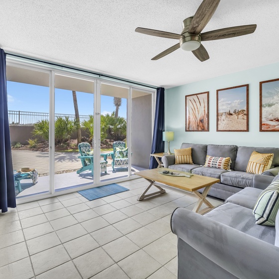 Relax in your spacious living room with ocean breezes from the ceiling fan and stunning patio views through floor-to-ceiling glass doors.