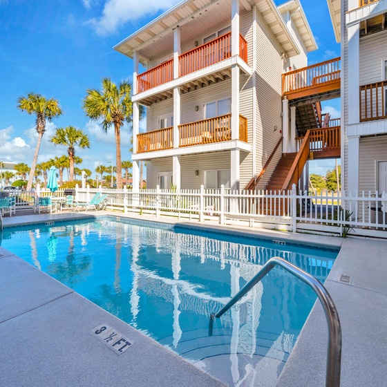 Sunset Cottages pool surrounded by tropical palms and charming beach-style buildings with inviting balconies.