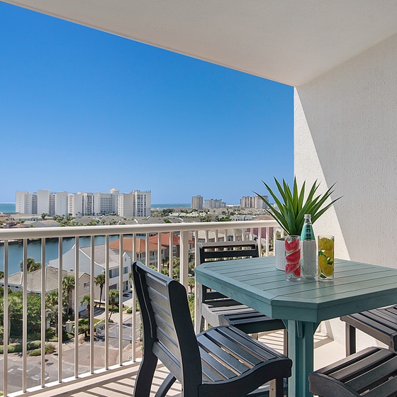 Elevated beachfront balcony with city views and outdoor dining table for four guests.
