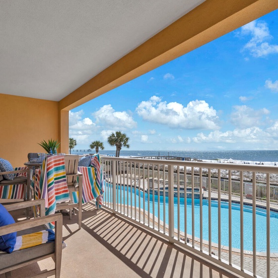 Step onto your private balcony and soak in stunning beach views while lounging in comfort with colorful towels and cozy seating.