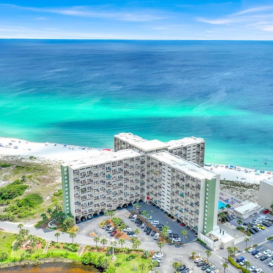 Beachfront resort complex featuring pristine white sand and emerald waters just steps from multiple property buildings.