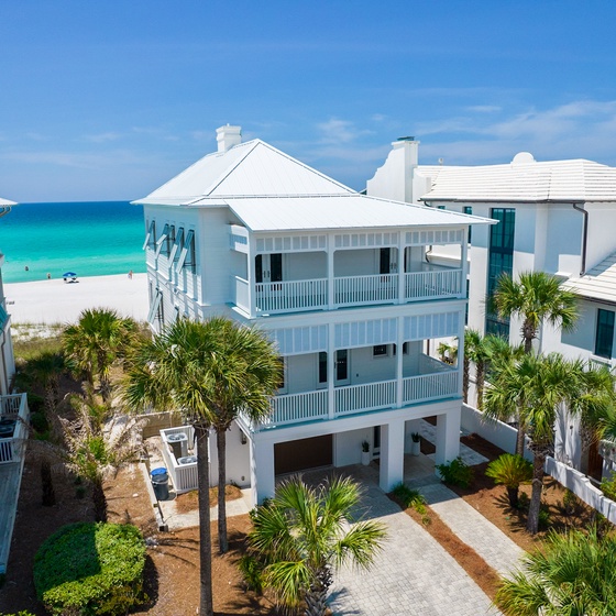 Beachfront property featuring white coastal architecture with multiple balconies and tropical landscaping, steps from pristine turquoise waters.