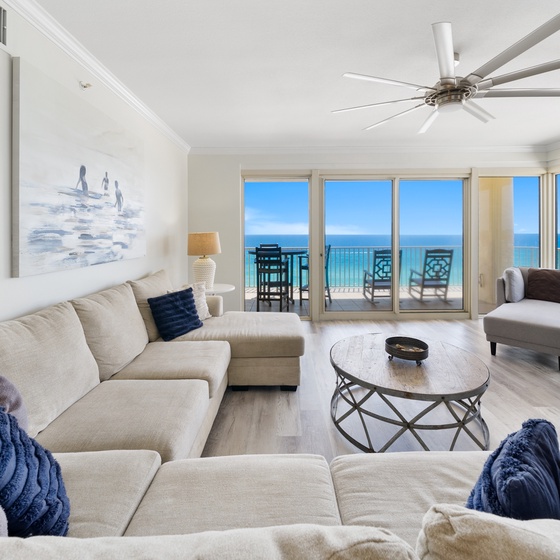 Sink into plush seating while ocean waves fill your view through floor-to-ceiling windows in this bright, coastal living space.