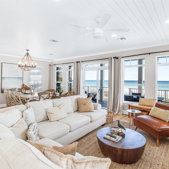 Sink into plush sofas while ocean waves sparkle through floor-to-ceiling windows in your bright, coastal living space.