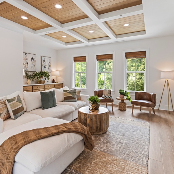 Sink into plush seating beneath stunning coffered ceilings where natural light floods through oversized windows, creating your perfect retreat.