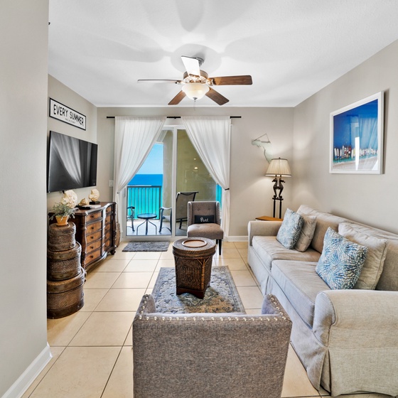 Your bright living room opens to a private balcony where ocean views greet you through flowing curtains.