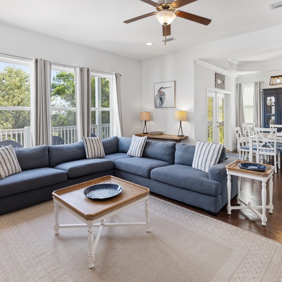 Sink into the plush sectional and let the coastal breeze flow through as sunlight fills your open-concept living and dining space, perfect for gathering with loved ones.