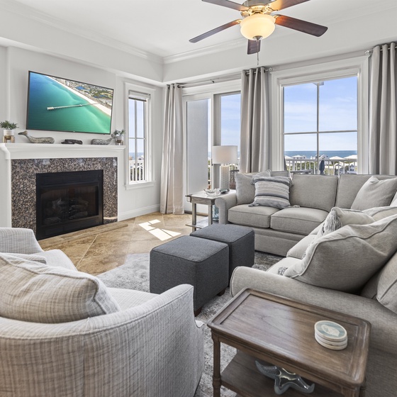 Unwind in your elegant living room with plush seating, cozy fireplace, and stunning ocean views through floor-to-ceiling windows.