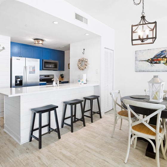 Your coastal-inspired kitchen and dining space features bright blue cabinets, modern appliances, and charming nautical artwork for memorable meals.