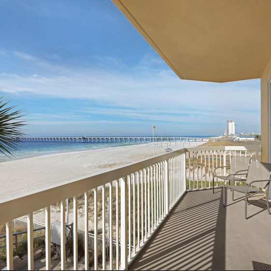 Expansive beachfront balcony offers stunning ocean views with white sand beach stretching endlessly beyond your private outdoor space.