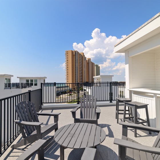 Rooftop terrace with comfortable seating overlooking the surrounding neighborhood under bright blue skies.