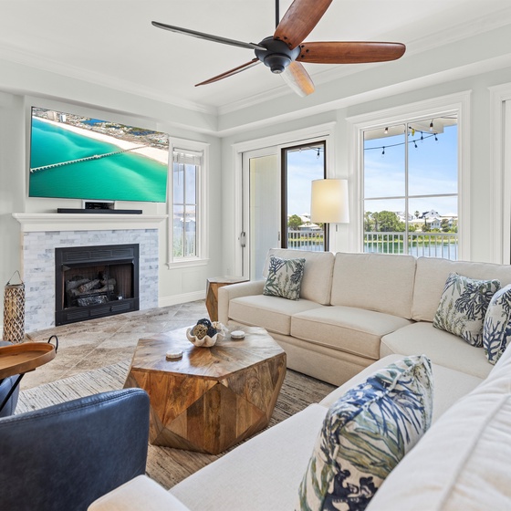 Unwind in this elegant living room with waterfront views, cozy fireplace, and comfortable sectional seating perfect for relaxing evenings.