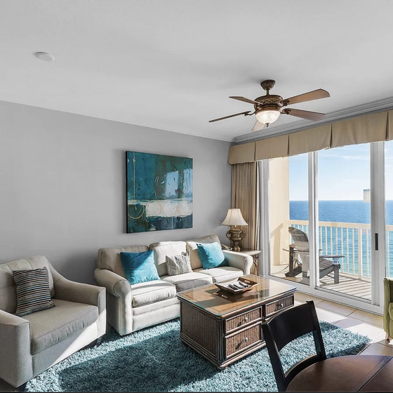 Relax in your bright living space with stunning ocean views through floor-to-ceiling windows and comfortable seating perfect for unwinding.