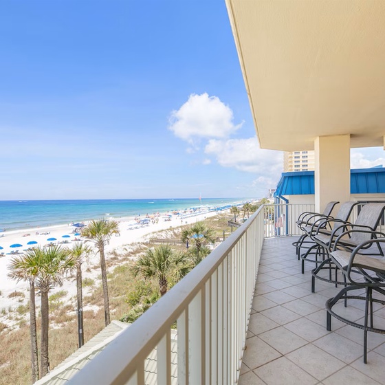 Relax on your private balcony with stunning ocean views, watching beachgoers enjoy the pristine white sand below.