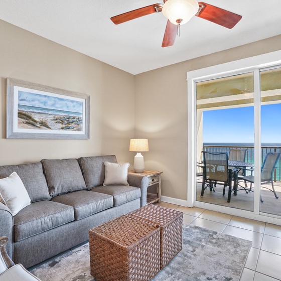Your coastal living room awaits with plush seating and stunning ocean views through floor-to-ceiling windows that frame the turquoise waters perfectly.