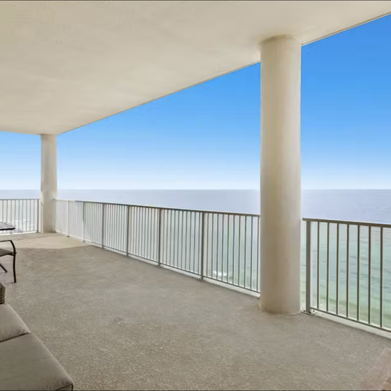 Expansive oceanfront balcony with outdoor seating overlooking pristine waters and clear skies.