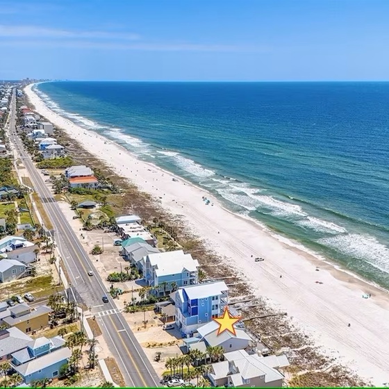 Aerial view of beachfront community with pristine sandy shores and turquoise waters stretching along the coast.