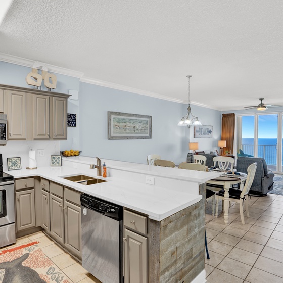 Your modern kitchen opens to the living area with stunning ocean views through floor-to-ceiling windows—perfect for morning coffee with endless blue horizons.