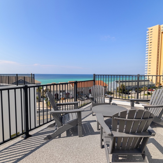 Soak in sweeping ocean views and coastal breezes from your private rooftop terrace, where comfortable seating invites you to unwind under clear blue skies.