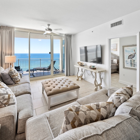 Relax in your bright living room with stunning ocean views through floor-to-ceiling windows and comfortable seating.