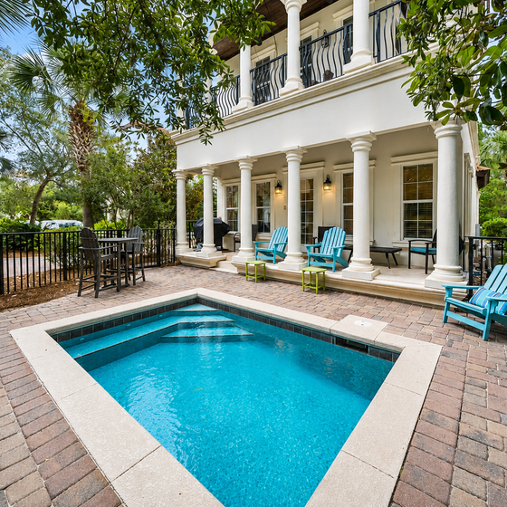 Your private oasis awaits with sparkling pool, elegant columns, and comfortable seating surrounded by lush tropical landscaping.