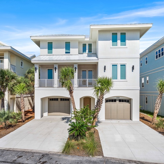 Modern coastal architecture welcomes guests to this pristine beach community property, featuring tropical landscaping and convenient parking.