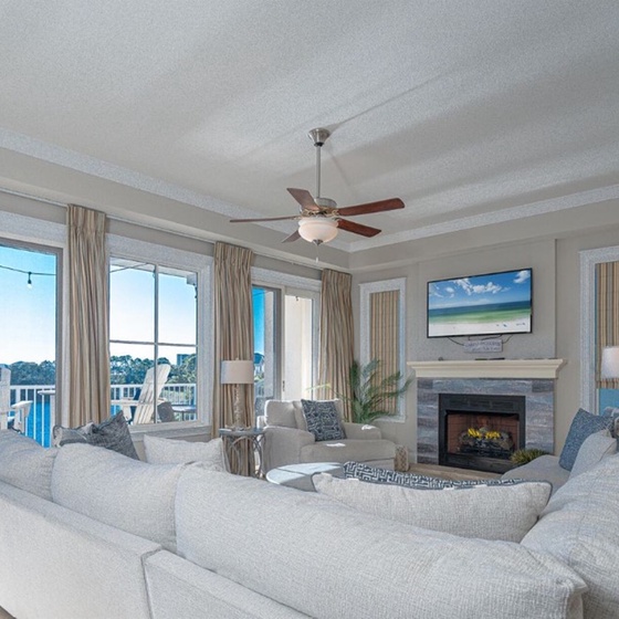 Unwind in your bright living room with plush seating, cozy fireplace, and gorgeous water views through floor-to-ceiling windows.