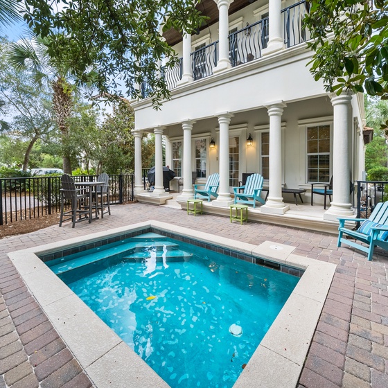 Your private oasis awaits with sparkling pool, elegant columns, and comfortable seating surrounded by lush tropical landscaping.
