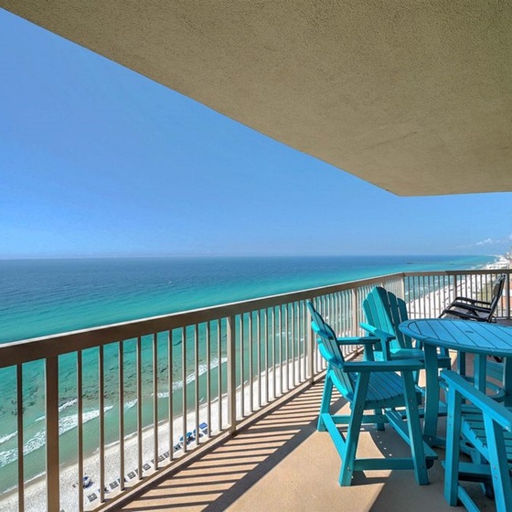 Your private oceanfront balcony features turquoise dining chairs and stunning sea views—perfect for morning coffee or sunset dinners.