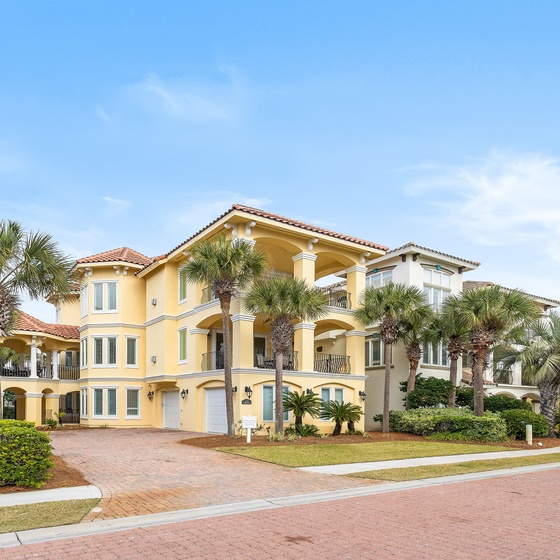 Stunning Mediterranean-style villa with palm trees and elegant architecture in an upscale coastal neighborhood.