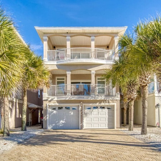Stunning beachside property featuring elegant balconies and tropical palm trees under brilliant blue skies.