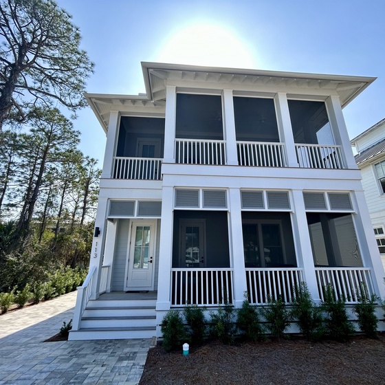 Beautiful two-story coastal home nestled among mature trees, featuring classic white architecture with wraparound porches and modern comfort.