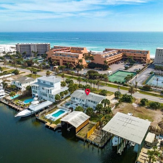 Coastal community aerial view showcasing waterfront properties, tennis courts, and beachfront hotels along pristine shores.