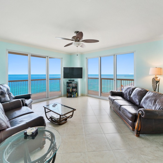 Relax in your oceanfront living room with stunning sea views through floor-to-ceiling windows. Comfortable leather seating invites you to unwind.