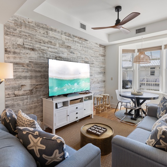 Unwind in your stylish living space with coastal charm, featuring comfortable seating, entertainment center, and dining area perfect for relaxing evenings.