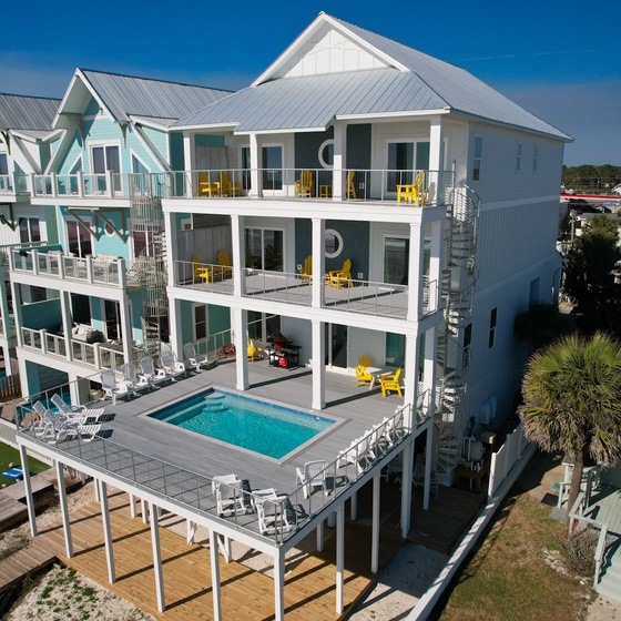 Modern beachfront rental with private pool, multiple decks, and bright yellow accents in a coastal community.