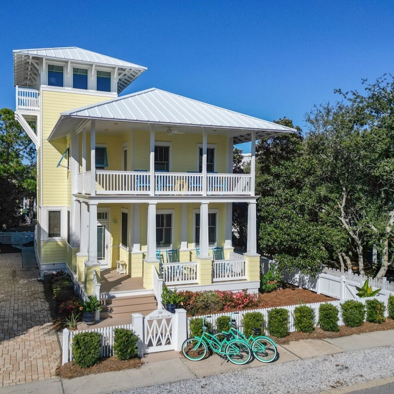 Charming beach house with wraparound porches, tower lookout, and coastal-style architecture in a peaceful neighborhood setting.
