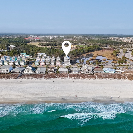 Aerial view of beachfront vacation rental location with pristine white sand beach and turquoise waters just steps away from the property.