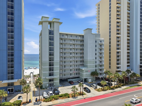 Beachfront resort property situated steps from sandy shores, surrounded by palm-lined streets in a vibrant coastal community.