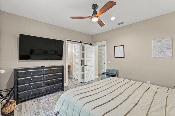 Unwind in your serene retreat with a ceiling fan overhead, a cozy bed calling you to relax, and a barn door adding charm as it opens to your private ensuite.