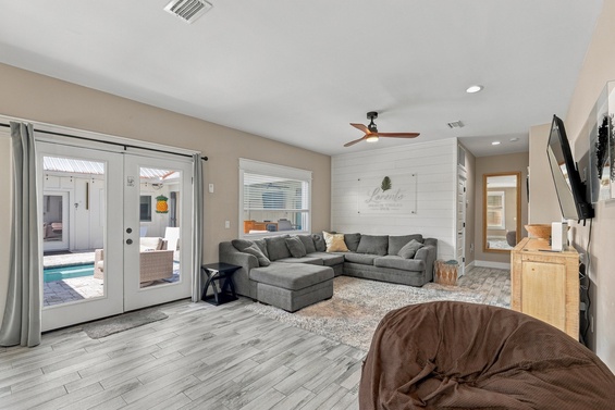 Step into your open-concept living room, where soft textures and coastal-inspired décor create a peaceful retreat. Relax on the sectional or step through the glass doors to your private pool and patio beyond.