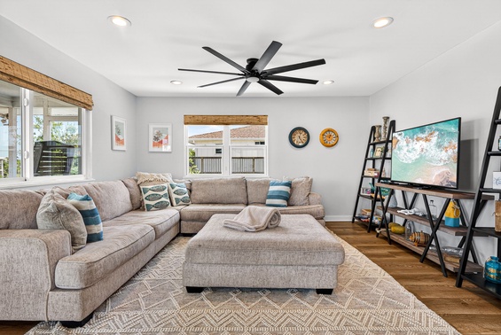 Unwind on the plush sectional in this bright, coastal-inspired living space. Relax under the breeze of the modern ceiling fan, catch your favorite shows on the large TV, and enjoy natural light streaming through bamboo-shaded windows.